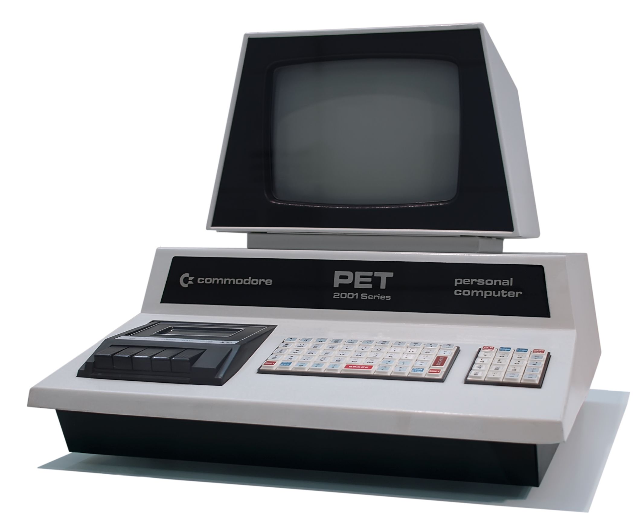 Photo of the PET computer on a white background. The machine has a single integrated body, keyboard, and screen with a build-in tape deck and an early Star Trek vibe.