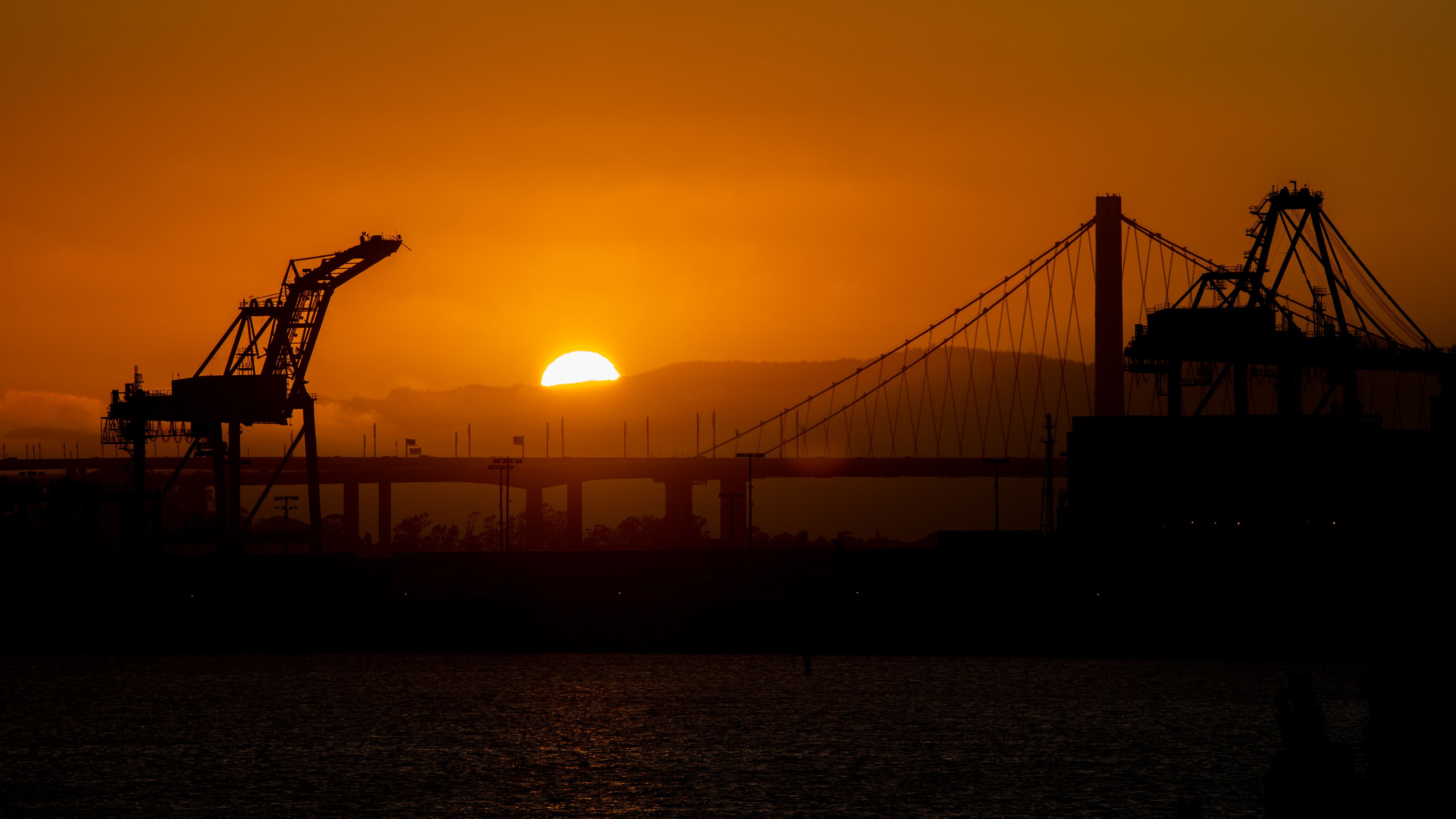 Sunset over a bridge and industrial cranes